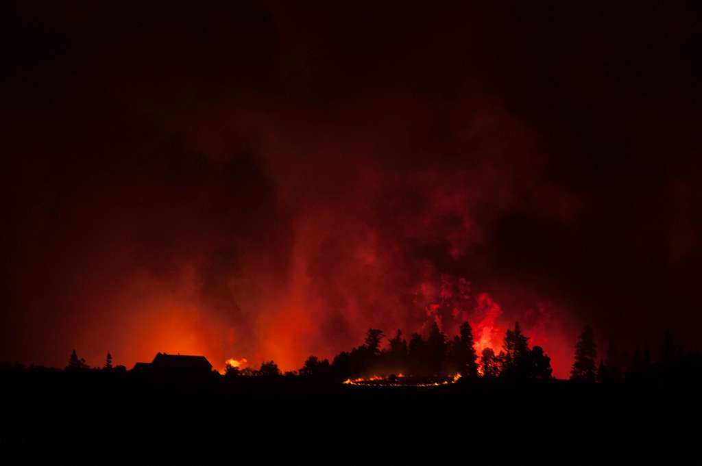 Dark mountain range illuminated by red and orange wildfire 