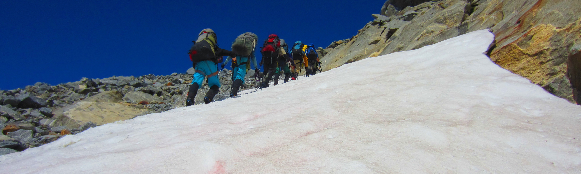 Field team walking up a glacier with climbing gear