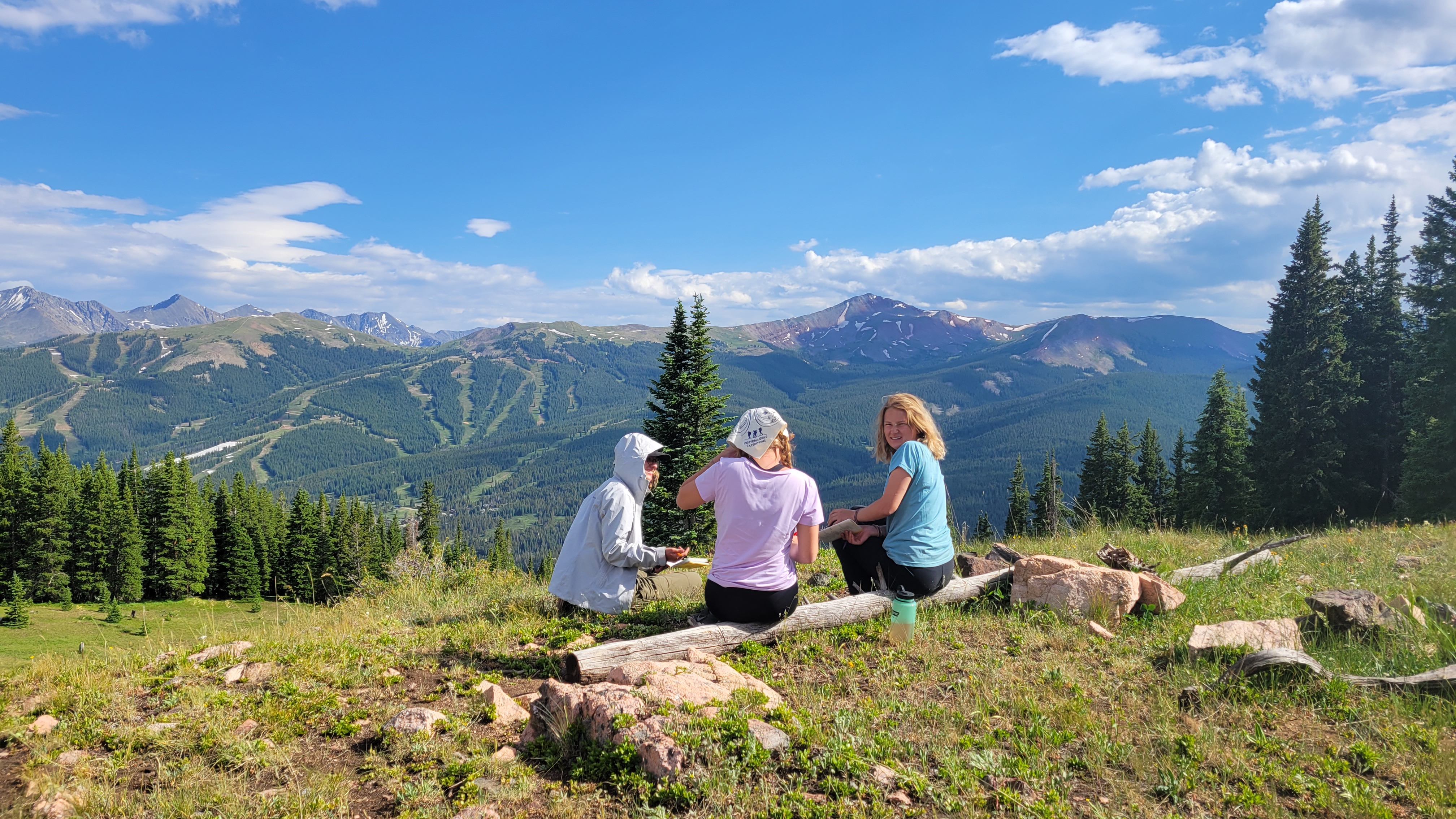 Girls sitting on side of mountain