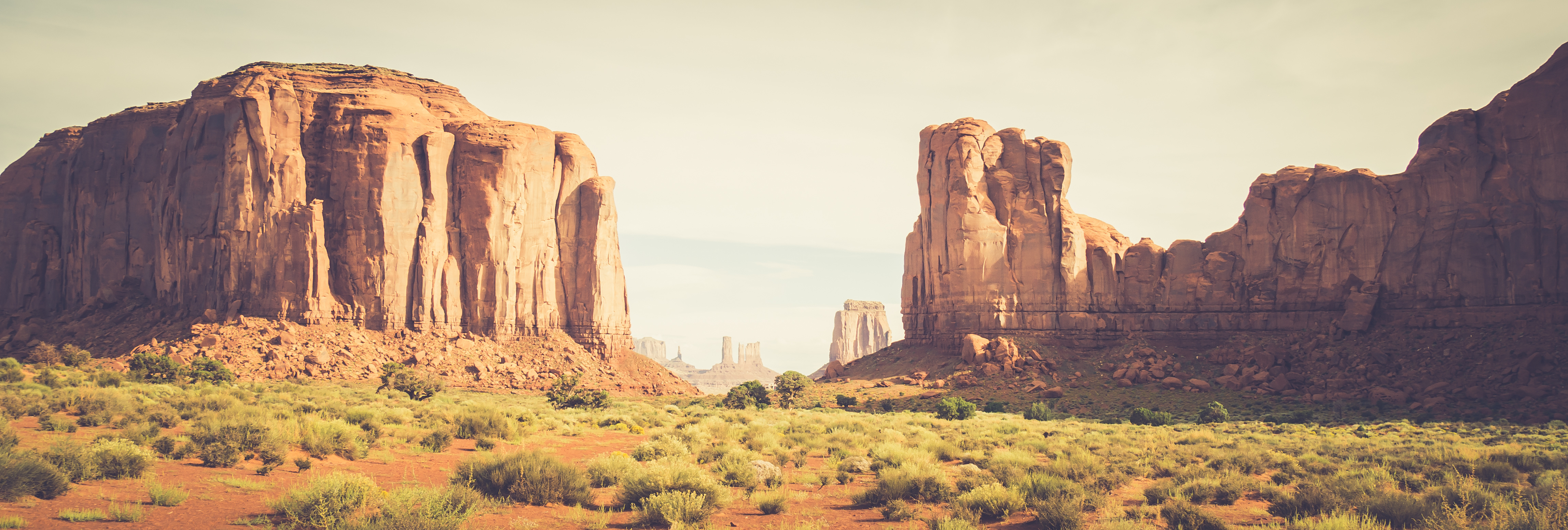Two table top mountains in Utah with green field in between it