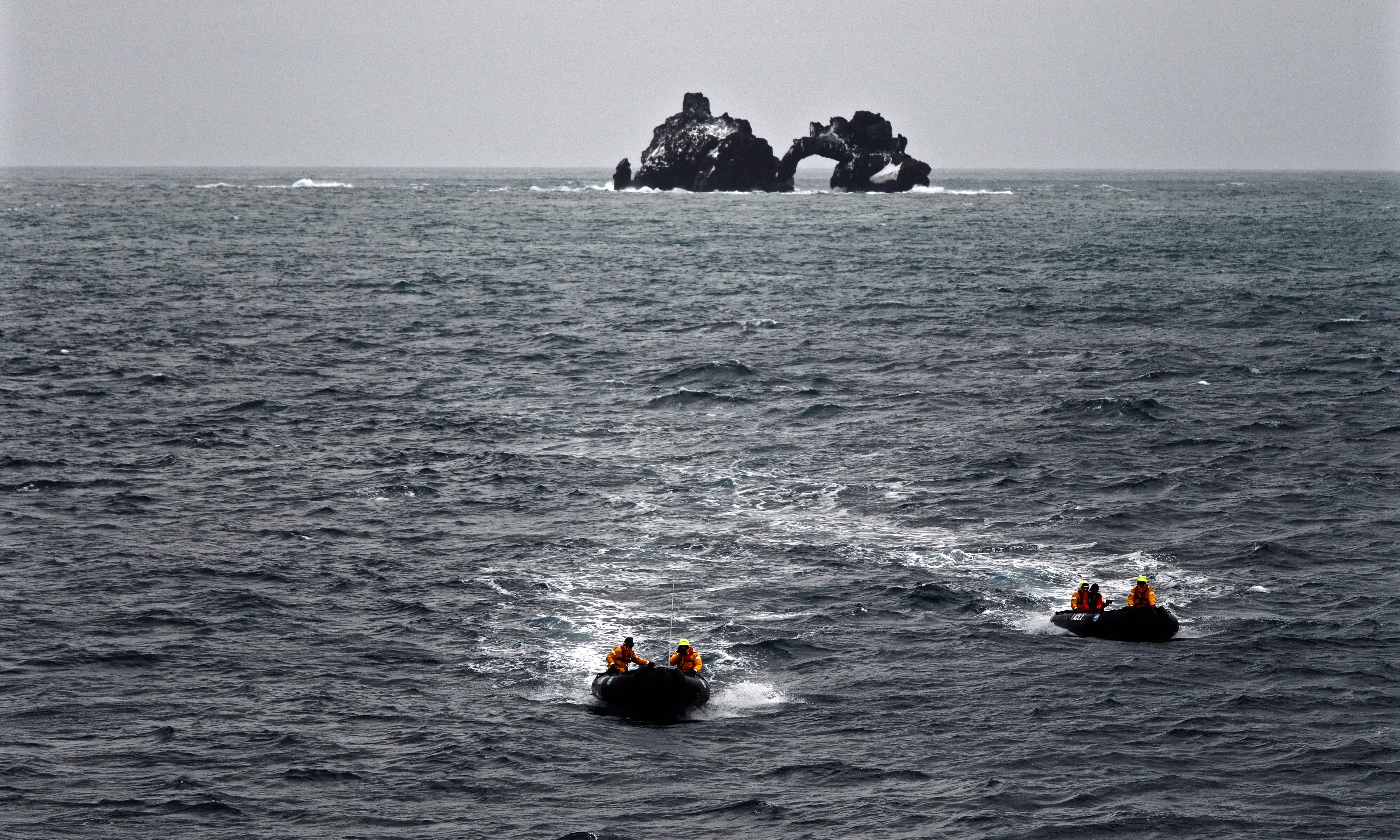 People on two separate boats speeding away from an island