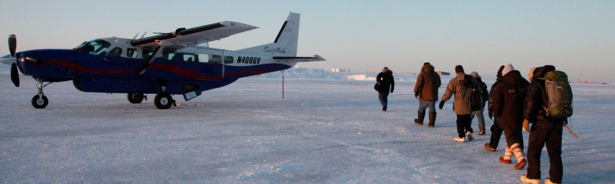 People walking towards and airplane on a icy field during winter