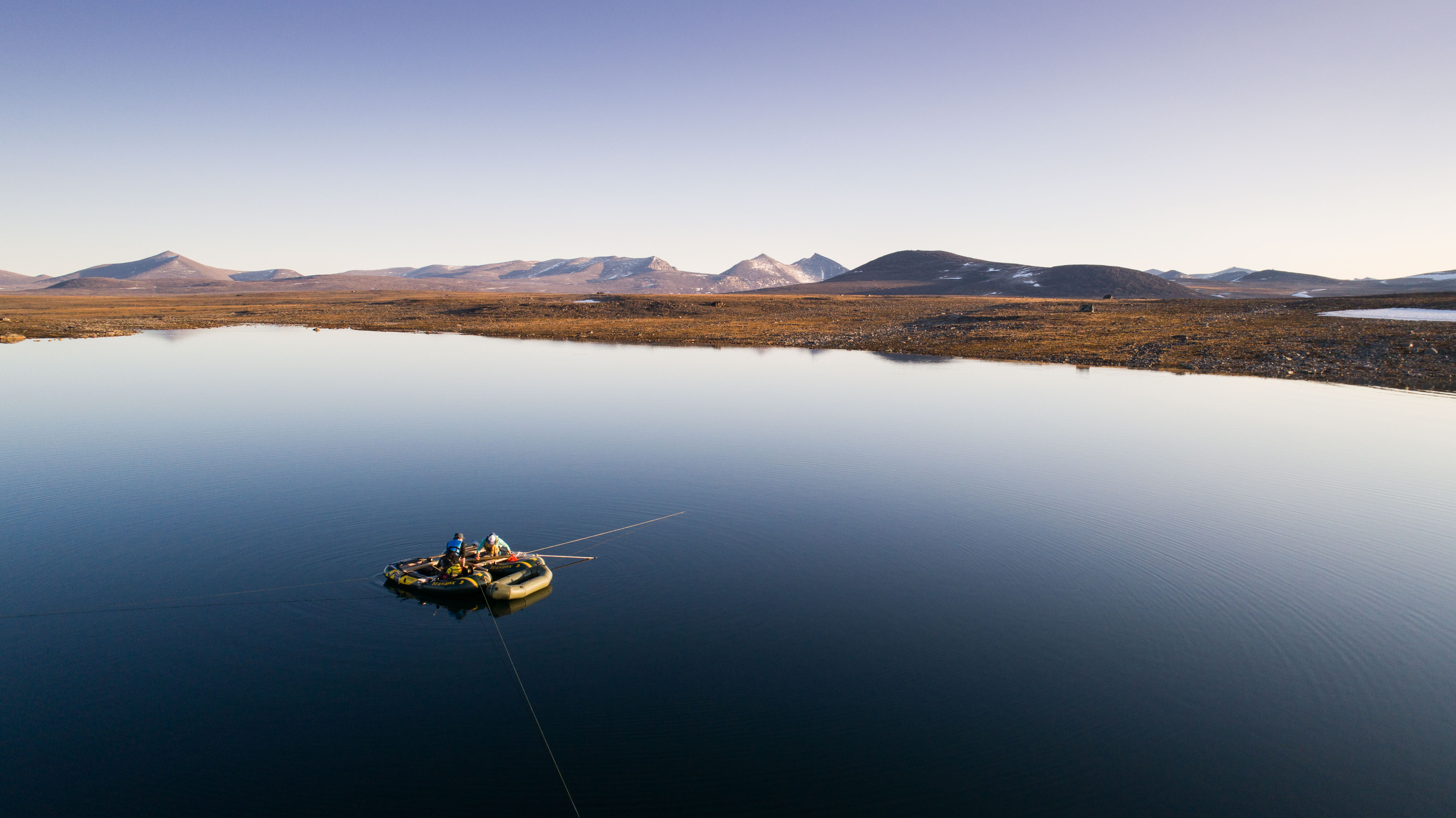 Ocean with one boat and a mountain range in the back at evening time