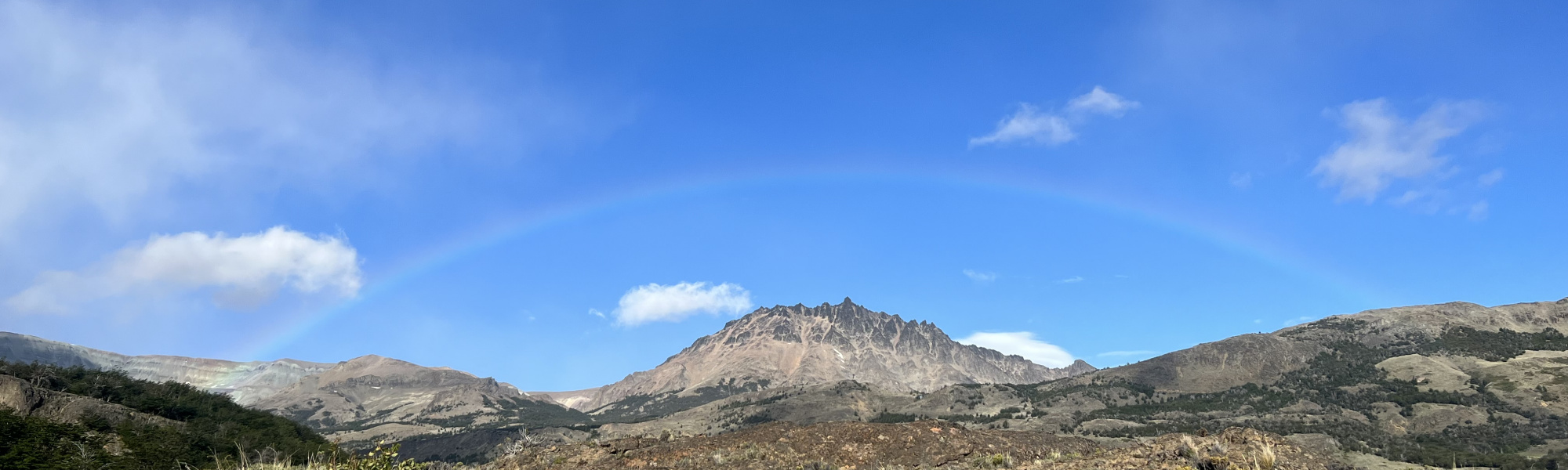 Rainbow over mountain range with blue skys 