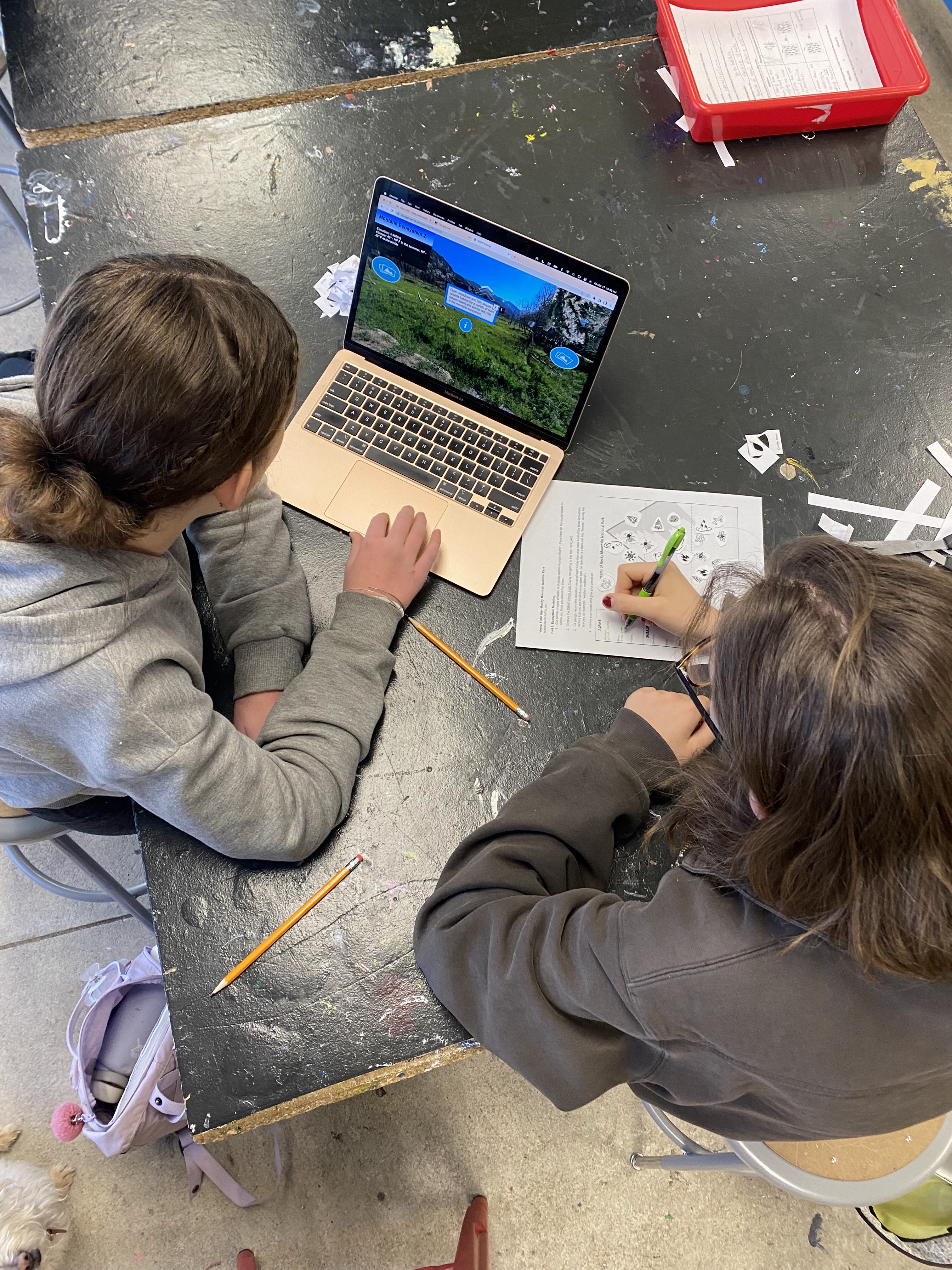 Two people writing and looking at a computer