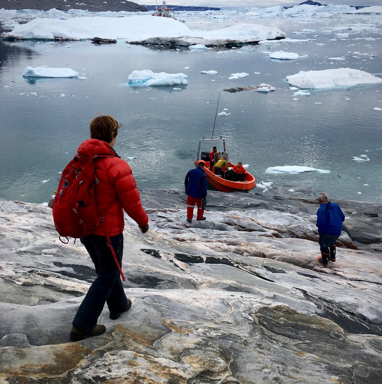 People walking towards ocean with icebergs during winter