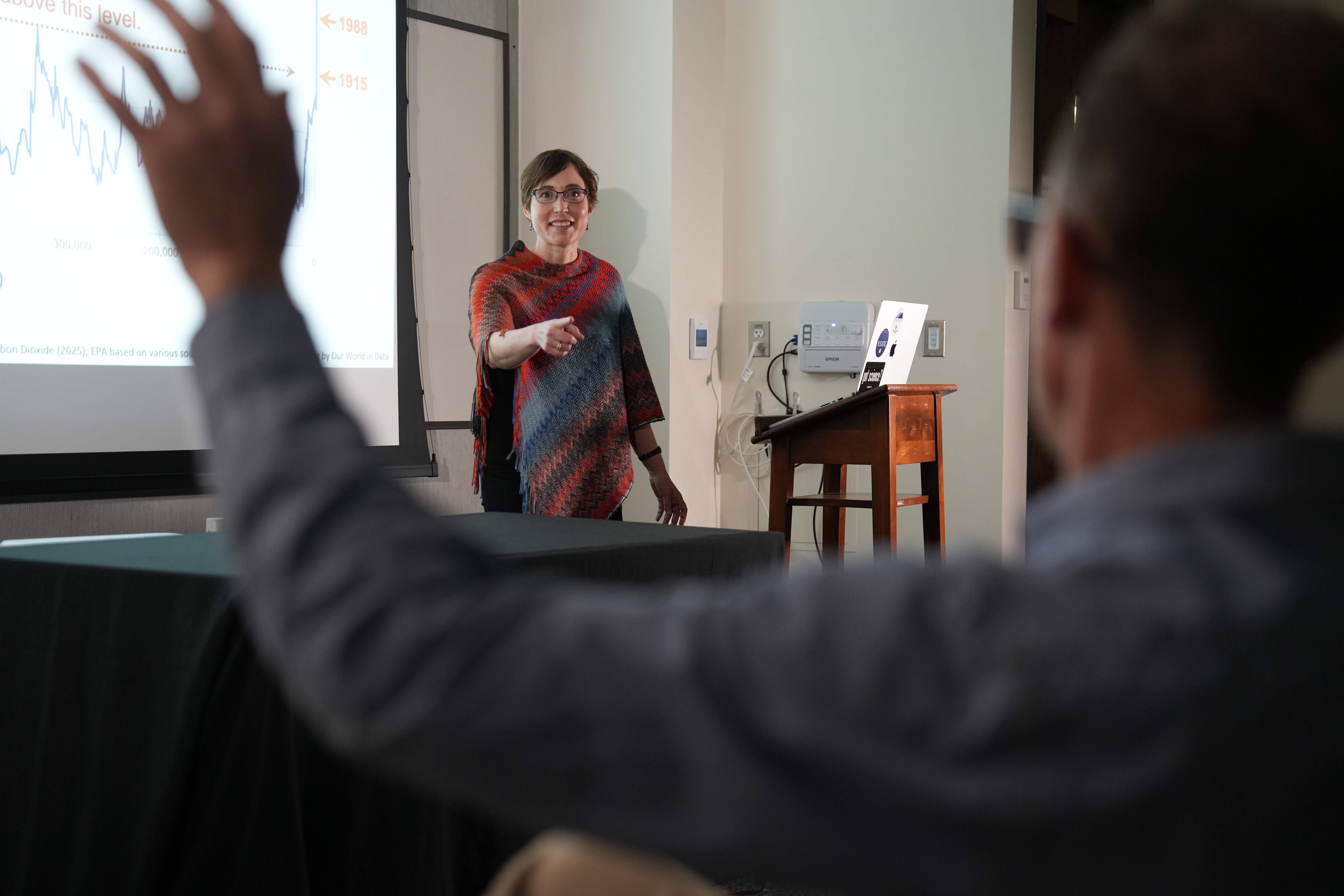 instructor before presentation, pointing at a spectator with a raised hand