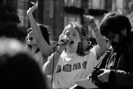 Black and white image climate protest with girl speaking into a microphone