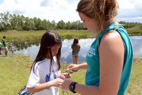 Teacher and student looking at something in students hand in nature