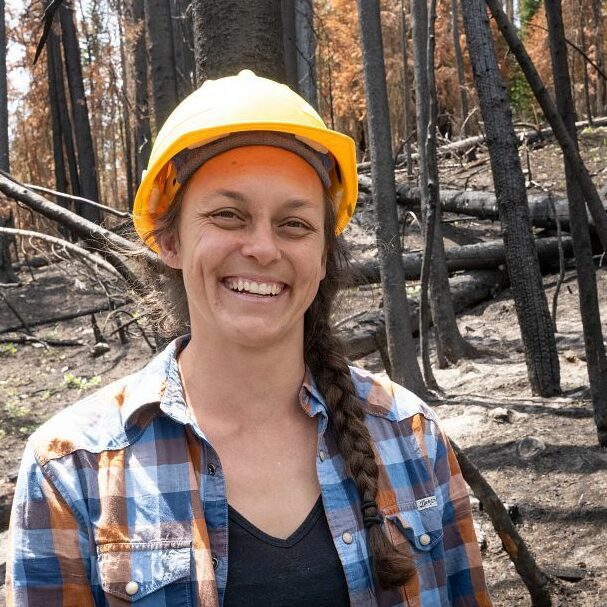 Camille Stevens-Rumann wearing a yellow hard hat and blue flannel in the woods