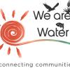 “Logo for ‘We Are Water.’ On the left is a stylized orange spiral sun with paint-stroke rays. To the right, the words ‘We are Water’ appear in dark gray, with small icons integrated above and between the words: a flying bird, a desert plant, and a fish. A flowing brushstroke in orange to teal runs beneath the text. Below, the tagline reads ‘connecting communities.’” 