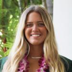 photo of Mara headshot-she is smiling with a green top and a pink flower lei necklace