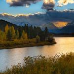 River running through mountain range at sunset during fall season