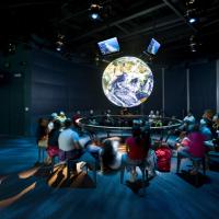 Students sit around a NOAA Science on a Sphere.