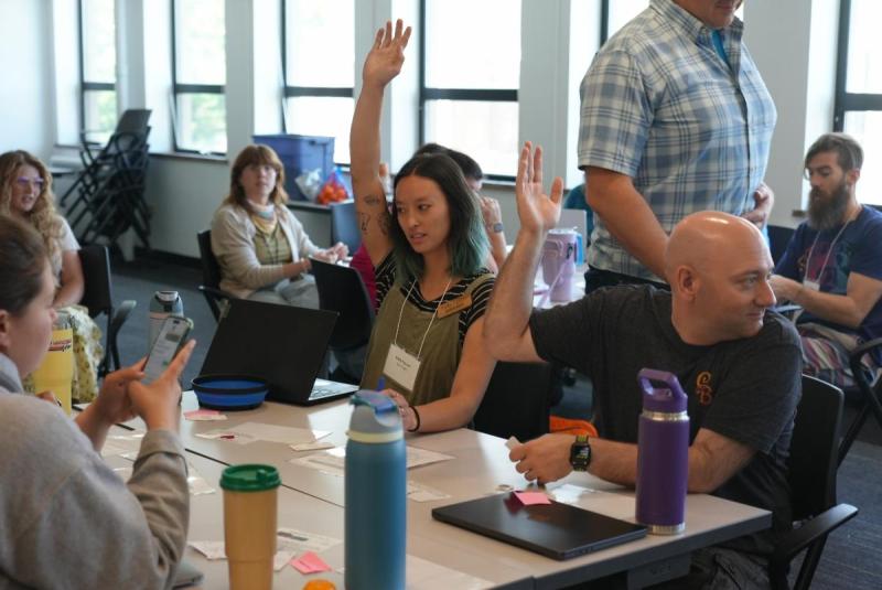 People in a classroom raising their hands