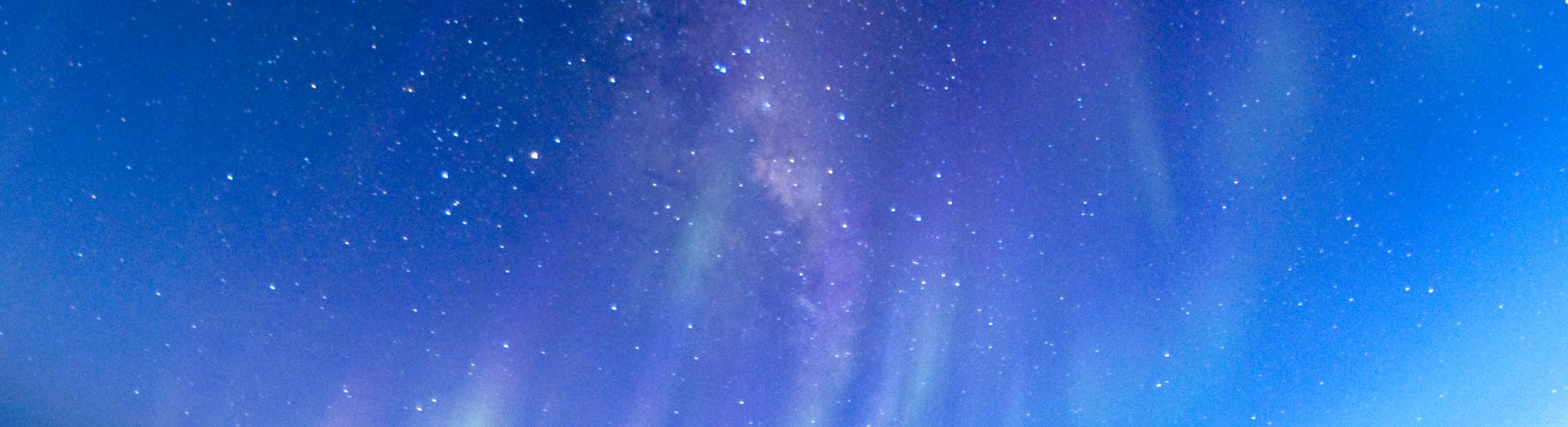 Stars and shafts of light above landscape 