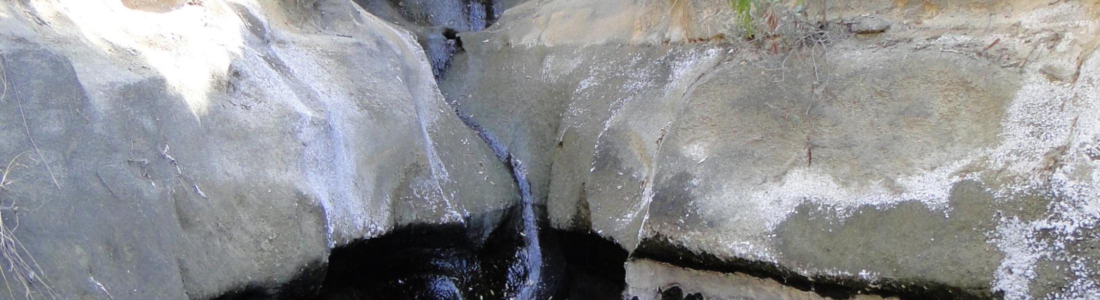 water trickles down rock walls along narrow canyon