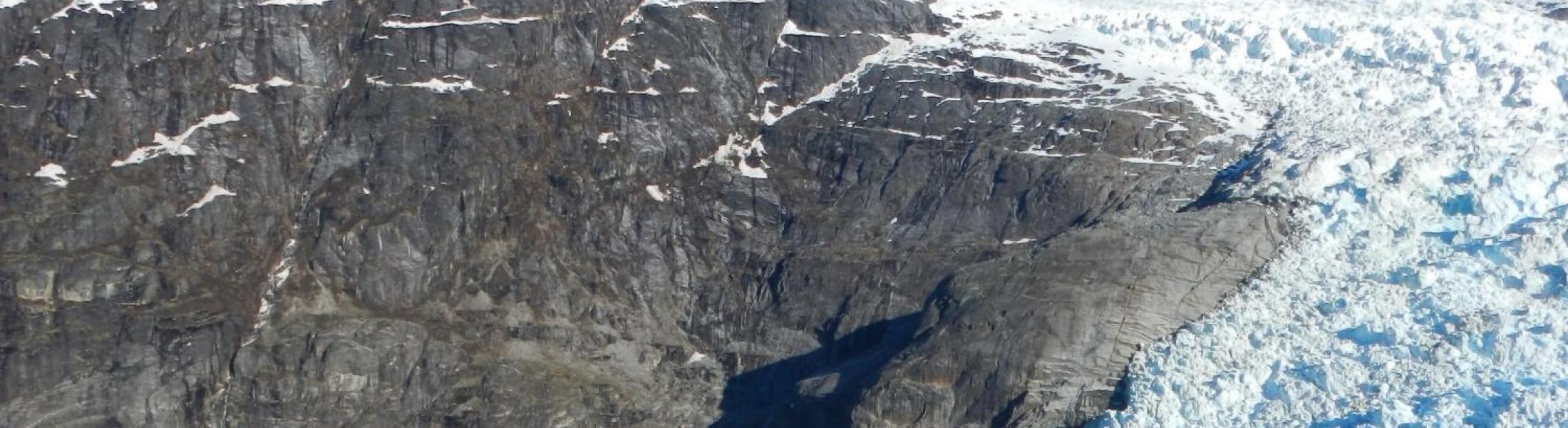 Dr. Twila Moon stands in front of melting snowpack and a distance mountain.