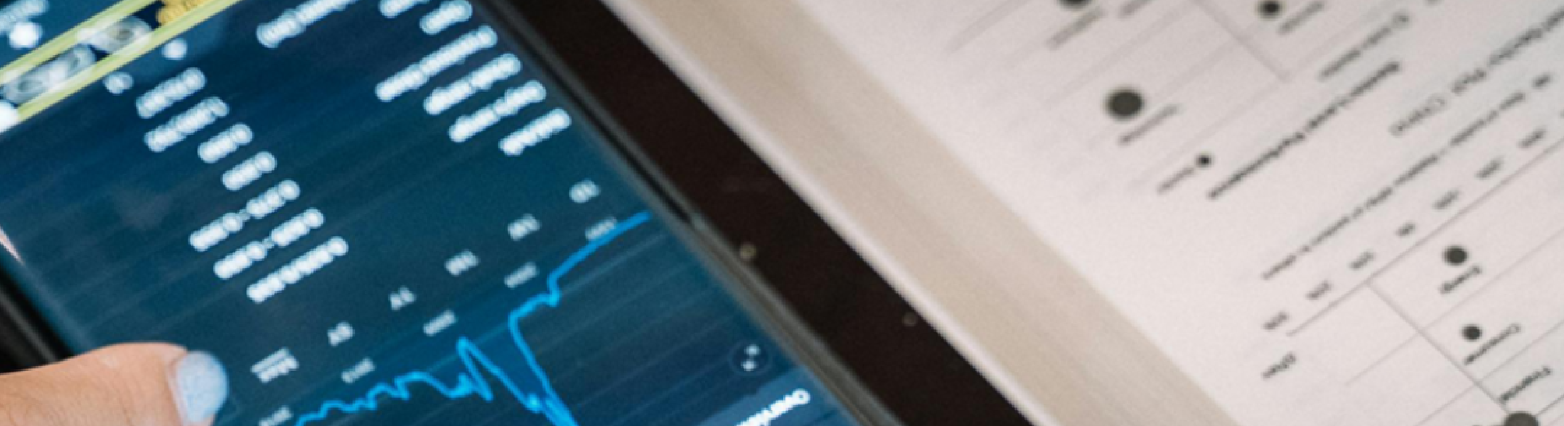 A hand scrolls on a phone aside a textbook.