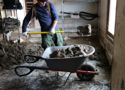 Shoveling mud out of the store room in Scotty's Castle Visitor Center. NPS.