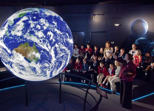 People looking at a globe simulation