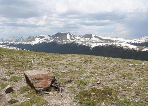Rocky Mountain National Park; rock in the forefront with snowy peaked mountains in the background