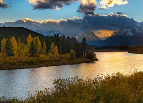 River running through mountain range at sunset during fall season
