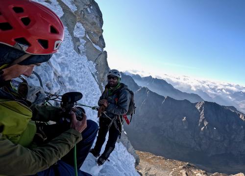 Ryan Vachon filming a climber on the side of a snowy mountain