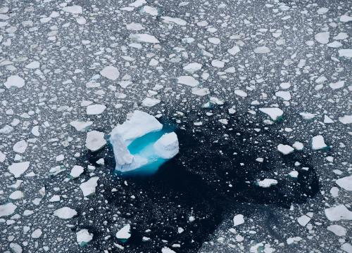 Melting bits of ice float over a deep blue ocean in the arctic sea.
