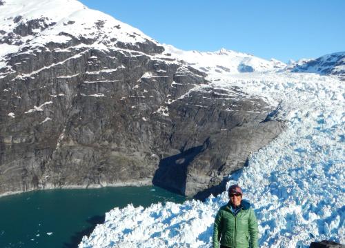 Dr. Twila Moon stands in front of melting snowpack and a distance mountain.