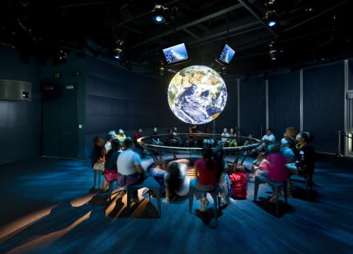 Students sit around a NOAA Science on a Sphere.