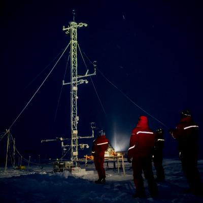 Scientists stand around a tall piece of scientific equipment.