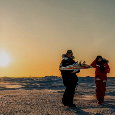 MOSAiC scientists holding an unmanned aerial aircraft in the Arctic.