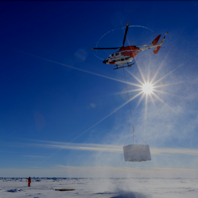 A helicopter is used to move heavy equipment around the ice.