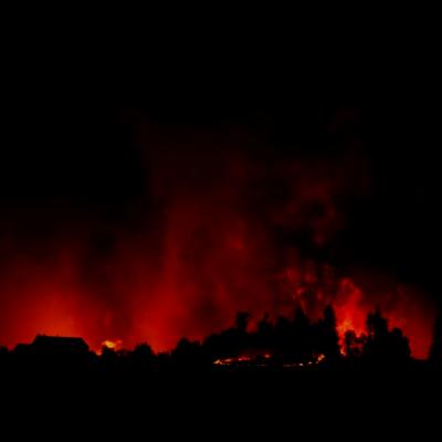 Dark mountain range illuminated by red and orange wildfire 