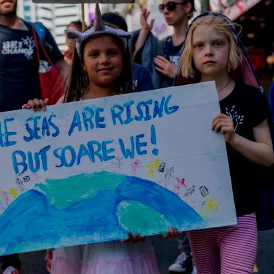 The seas are rising and so are we children holding up poster