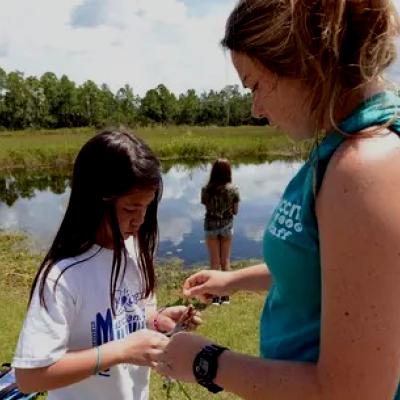 Student and teacher looking at something in students hand in nature