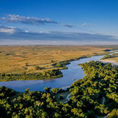 River running through valley with grassland and green trees