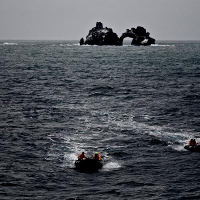 People on two separate boats speeding away from an island