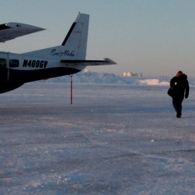 People walking towards and airplane on a icy field during winter