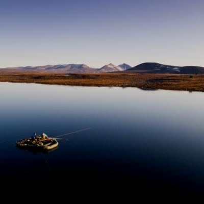 Ocean with one boat and a mountain range in the back at evening time
