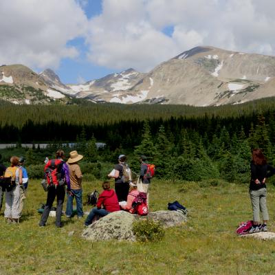 Students apart of the RECCS program standing in the middle of a field in the mountains with backpacks on