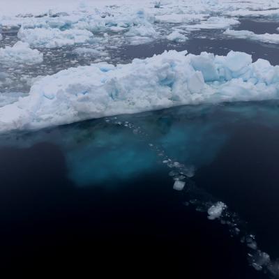 Ice berg floating in the ocean with blue water