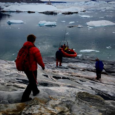 People walking towards ocean with icebergs during winter
