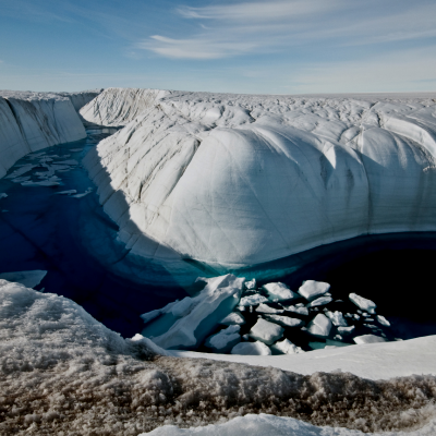 River going through a channel in between a glacier, water is dark blue
