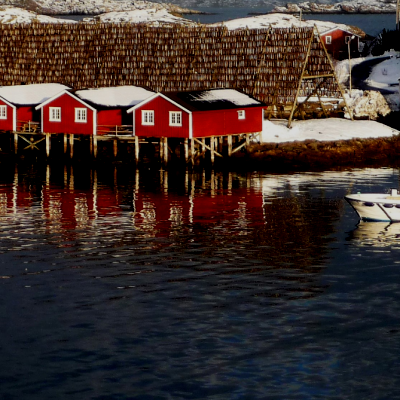 Red, white and brown houses on the ocean in winter with boat 