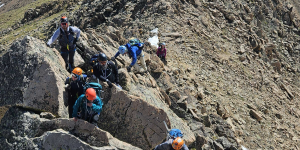 Field group climbing up side of mountain ridge