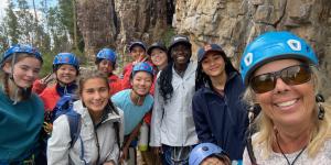 Group of women smiling wearing helmets outside by cliff face