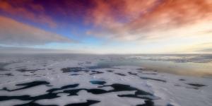 Ocean covered in ice and snow with sunset, purple, orange, blue colors