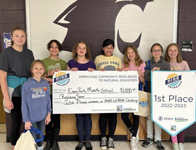 A group of kids holding a large check and a first place sign